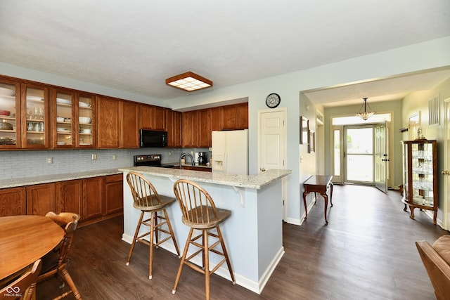 938 Weeping Way Ln, Avon, IN 46123 - kitchen with white refrigerator with ice dispenser, black microwave, dark wood finished floors, brown cabinets, and decorative backsplash