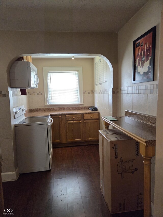 1168 N Gladstone Ave, Indianapolis, IN 46201 - kitchen featuring white appliances, dark wood-style floors, arched walkways, and tasteful backsplash