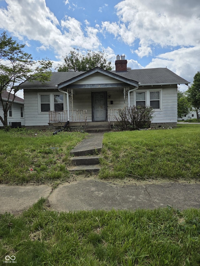 1168 N Gladstone Ave, Indianapolis, IN 46201 - bungalow with covered porch, a chimney, and a front lawn