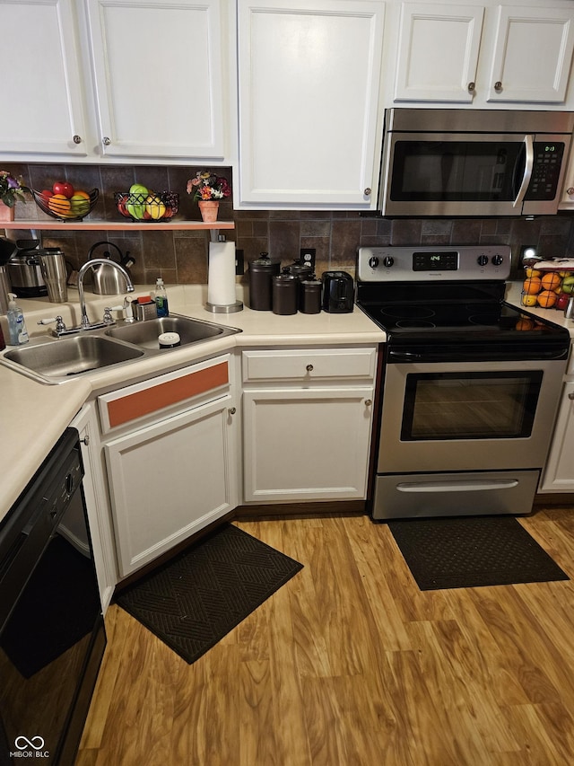 4962 Potomac Square Pl, Indianapolis, IN 46268 - kitchen featuring appliances with stainless steel finishes, a sink, white cabinets, backsplash, and light wood-style flooring