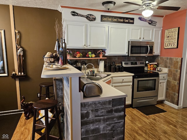 4962 Potomac Square Pl, Indianapolis, IN 46268 - kitchen with stainless steel appliances, a sink, a ceiling fan, white cabinets, and light countertops