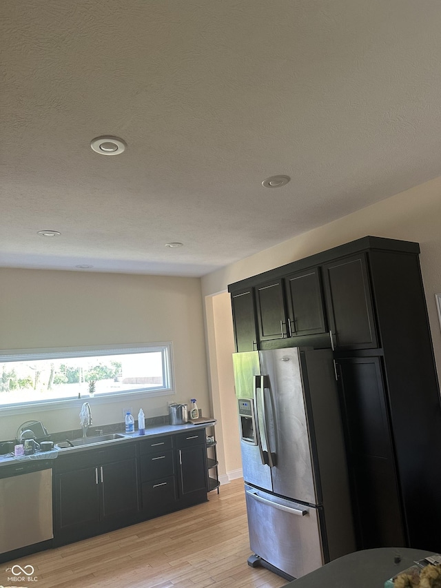 1128 S Pennsylvania St, Indianapolis, IN 46225 - kitchen with dark cabinetry, a sink, stainless steel fridge with ice dispenser, light wood-style flooring, and recessed lighting