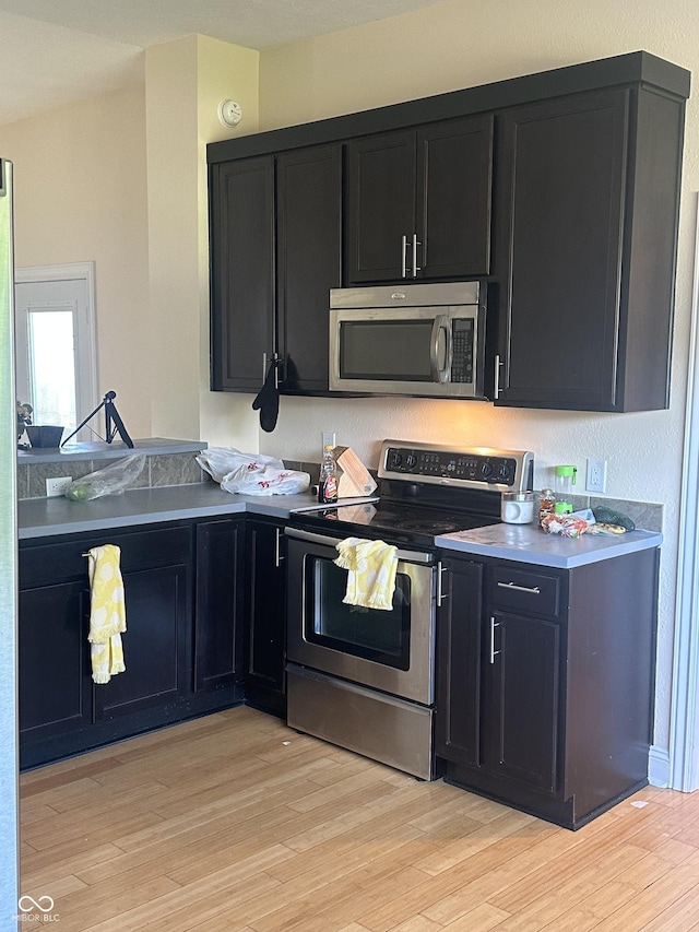 1128 S Pennsylvania St, Indianapolis, IN 46225 - kitchen featuring stainless steel appliances, dark cabinets, and light wood-type flooring