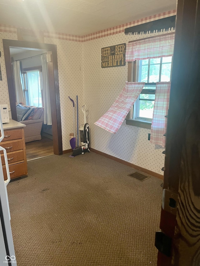 unfurnished bedroom featuring carpet, wallpapered walls, and baseboards