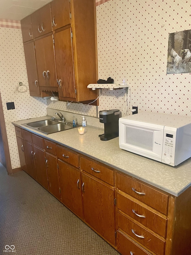 kitchen with white microwave, a sink, and light countertops