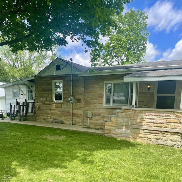 rear view of house featuring stone siding and a lawn