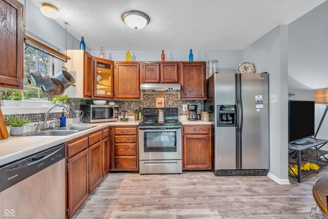 1104 Briarwood Dr, Brownsburg, IN 46112 - kitchen featuring stainless steel appliances, a sink, under cabinet range hood, light countertops, and light wood-style floors