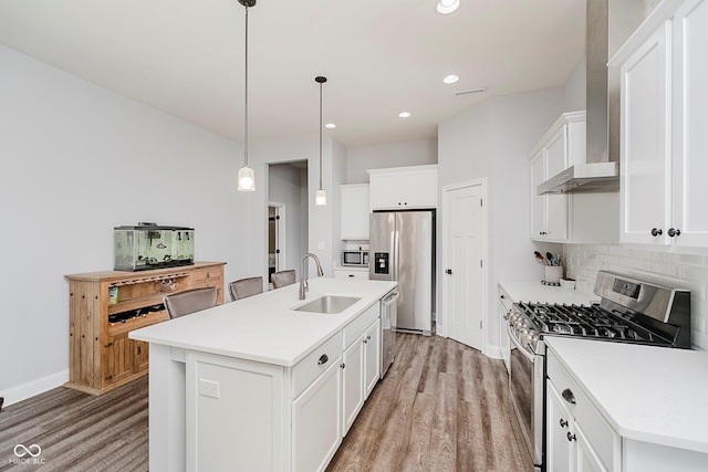 7077 Antiquity Dr, Carmel, IN 46033 - kitchen featuring a sink, stainless steel appliances, wall chimney range hood, light wood-style flooring, and a kitchen island with sink