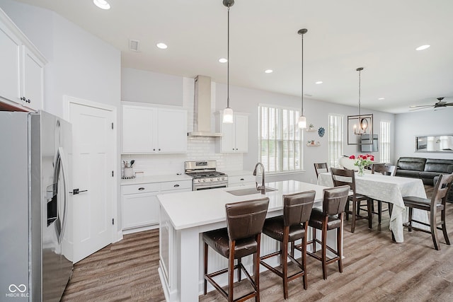 7077 Antiquity Dr, Carmel, IN 46033 - kitchen with stainless steel appliances, wall chimney range hood, a sink, light wood-type flooring, and a ceiling fan
