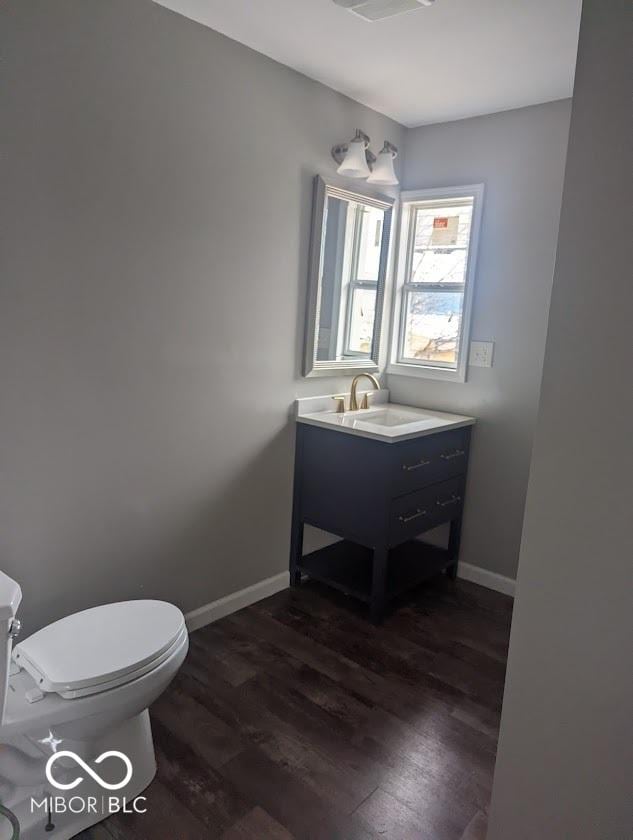 2968 N Arsenal Ave, Indianapolis, IN 46218 - half bathroom featuring wood finished floors, toilet, vanity, and baseboards