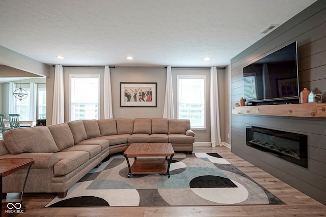 548 Gosford Ct, Westfield, IN 46074 - living room featuring wood finished floors, a glass covered fireplace, a textured ceiling, recessed lighting, and a chandelier