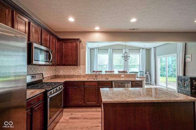 548 Gosford Ct, Westfield, IN 46074 - kitchen with appliances with stainless steel finishes, light stone countertops, light wood-type flooring, decorative backsplash, and a chandelier