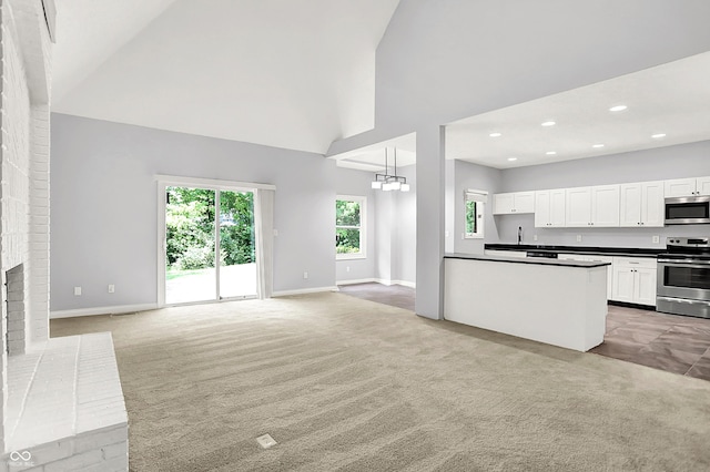 7513 Pine Royal Dr, Indianapolis, IN 46256 - unfurnished living room featuring high vaulted ceiling, plenty of natural light, light colored carpet, a chandelier, and recessed lighting