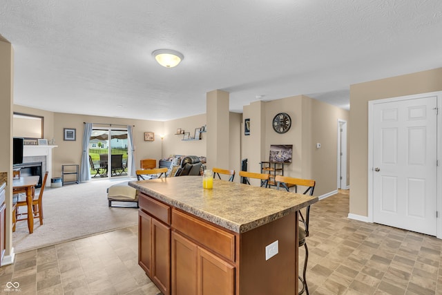 10731 Jimmy Lake Dr, Indianapolis, IN 46239 - kitchen featuring a kitchen bar, a kitchen island, open floor plan, a textured ceiling, and a fireplace