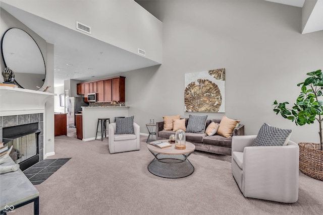 1064 Reserve Way, Indianapolis, IN 46220 - living room with a tile fireplace, light carpet, a towering ceiling, and baseboards