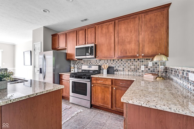 1064 Reserve Way, Indianapolis, IN 46220 - kitchen featuring appliances with stainless steel finishes, tasteful backsplash, a textured ceiling, brown cabinets, and light tile patterned flooring