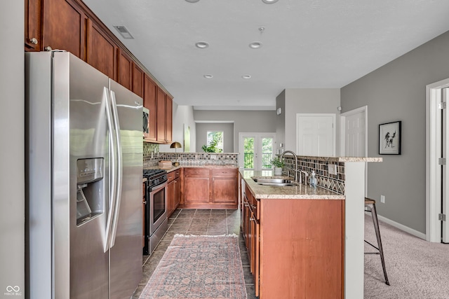 1064 Reserve Way, Indianapolis, IN 46220 - kitchen featuring appliances with stainless steel finishes, a sink, backsplash, a kitchen bar, and a kitchen island with sink