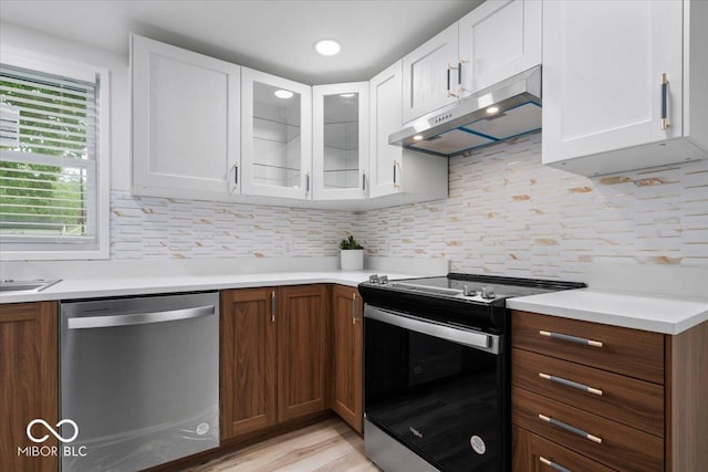 450 Historic Pleasant St, Noblesville, IN 46060 - kitchen with stainless steel appliances, under cabinet range hood, white cabinetry, light countertops, and glass insert cabinets