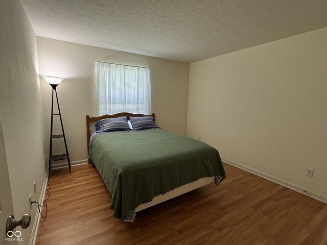 7970 Cobblesprings Dr, Avon, IN 46123 - bedroom with wood finished floors, a textured ceiling, and baseboards