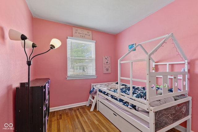 bedroom with wood-type flooring and baseboards