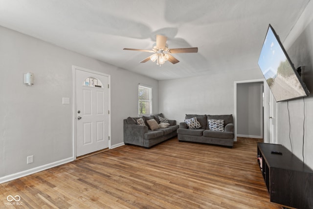 living area with a ceiling fan, wood finished floors, and baseboards