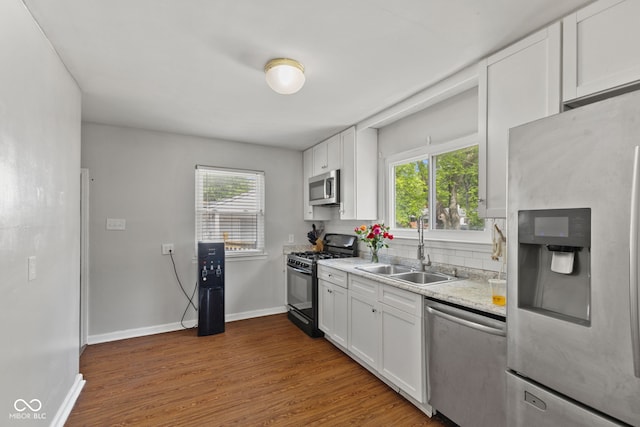 kitchen featuring appliances with stainless steel finishes, a sink, dark wood-style floors, and white cabinets