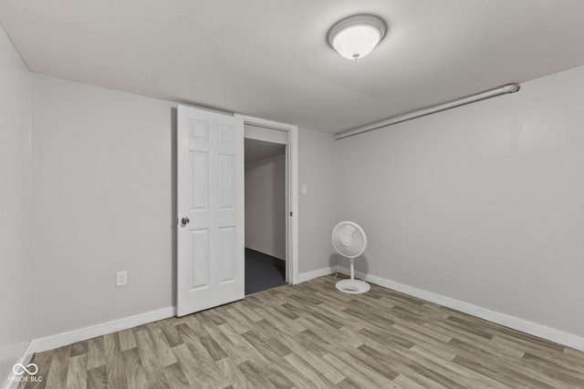 finished below grade area with light wood-style flooring and baseboards