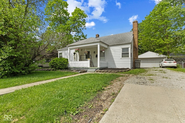 bungalow-style house with a porch, an outdoor structure, a front lawn, a garage, and roof with shingles