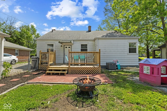 rear view of property with a fire pit, a wooden deck, cooling unit, a shingled roof, and a patio area