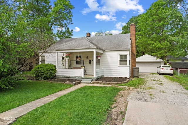 bungalow with a porch, roof with shingles, a chimney, an outdoor structure, and a detached garage
