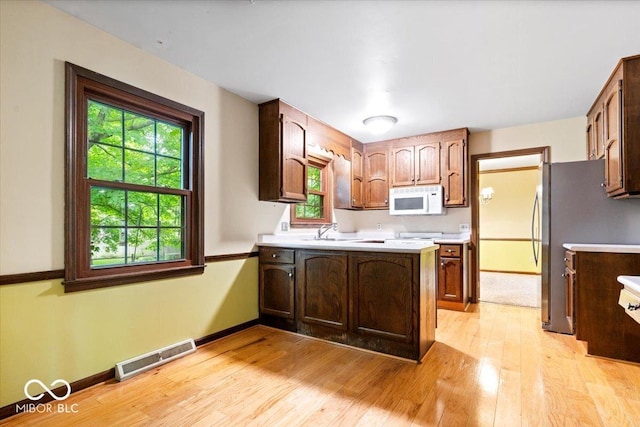 659 Carson Ct, Carmel, IN 46033 - kitchen with white microwave, light wood-style floors, light countertops, and plenty of natural light