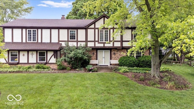 659 Carson Ct, Carmel, IN 46033 - tudor-style house featuring a front lawn, brick siding, a chimney, and stucco siding