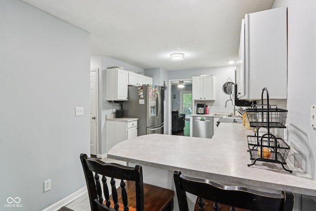 6804 Erika Ln, Nashville, IN 47448 - kitchen featuring appliances with stainless steel finishes, a peninsula, a breakfast bar, white cabinets, and a ceiling fan