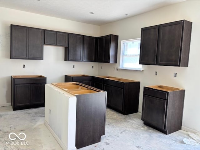 3897 Berkdale Ct, Columbus, IN 47203 - kitchen with a center island, baseboards, and dark brown cabinetry