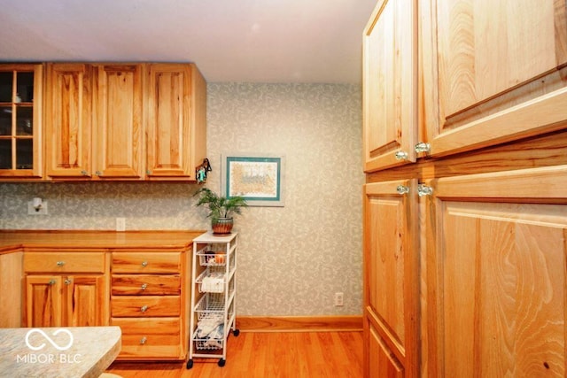 17310 N Willman Rd, Eaton, IN 47338 - kitchen featuring wallpapered walls, light wood finished floors, light countertops, baseboards, and glass insert cabinets