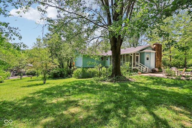 9240 E Woodview Dr, Bloomington, IN 47401 - view of grassy yard with a patio area, a sunroom, and entry steps