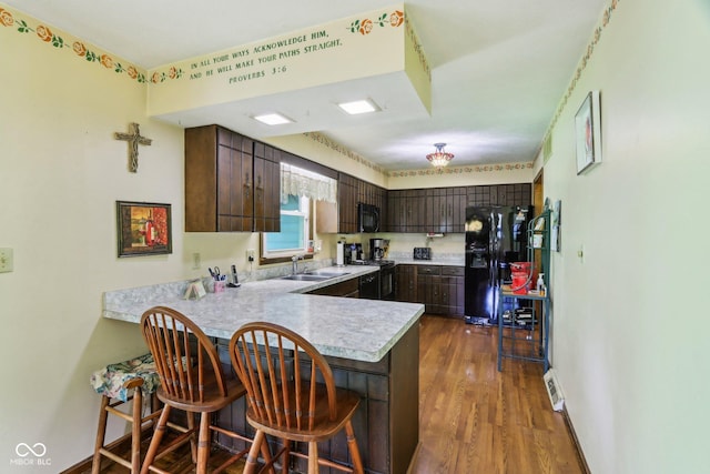 9240 E Woodview Dr, Bloomington, IN 47401 - kitchen with black appliances, a peninsula, light countertops, dark brown cabinets, and a breakfast bar area