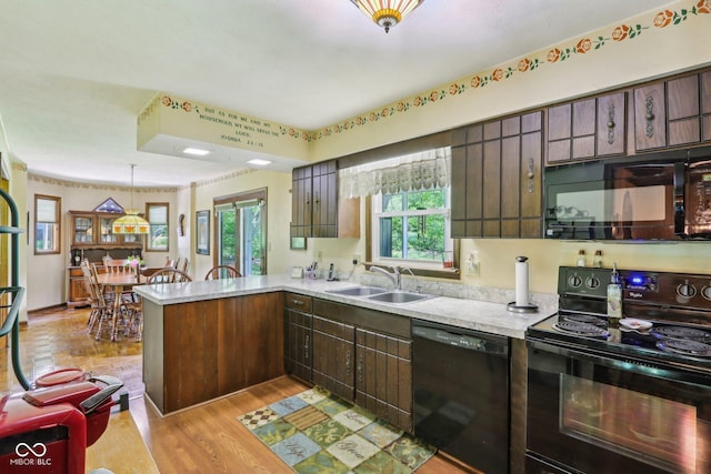 9240 E Woodview Dr, Bloomington, IN 47401 - kitchen with black appliances, a peninsula, light countertops, light wood-style flooring, and pendant lighting