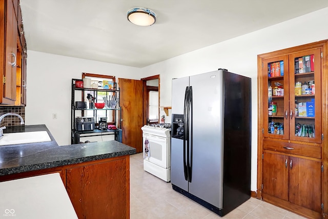 3310 Ransdell St, Indianapolis, IN 46227 - kitchen featuring stainless steel fridge, white gas stove, a sink, dark countertops, and brown cabinets