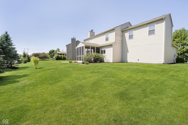 14135 Nicholas Dr, Carmel, IN 46074 - rear view of property with a chimney, a lawn, and a sunroom
