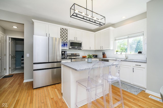 14135 Nicholas Dr, Carmel, IN 46074 - kitchen with stainless steel appliances, a sink, a center island, decorative backsplash, and light wood-style flooring