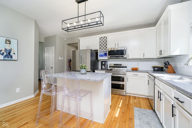 14135 Nicholas Dr, Carmel, IN 46074 - kitchen with appliances with stainless steel finishes, a sink, a kitchen island, backsplash, and light wood finished floors