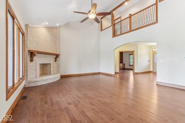 2825 S State Road 267, Plainfield, IN 46168 - unfurnished living room featuring ceiling fan, arched walkways, a fireplace, high vaulted ceiling, and wood finished floors