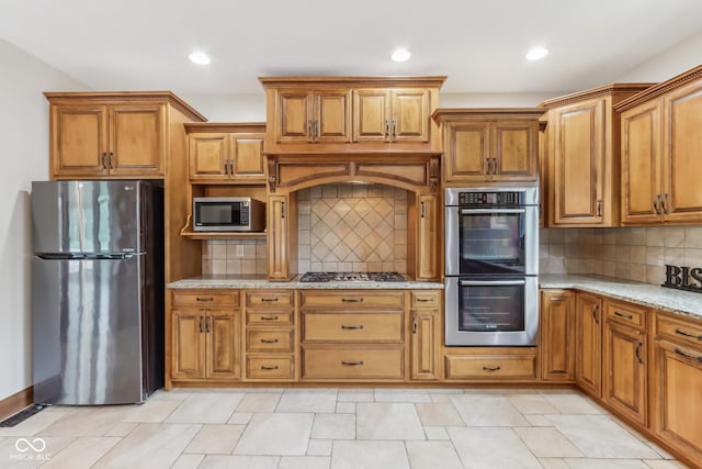 2825 S State Road 267, Plainfield, IN 46168 - kitchen featuring appliances with stainless steel finishes, brown cabinets, light stone counters, backsplash, and recessed lighting