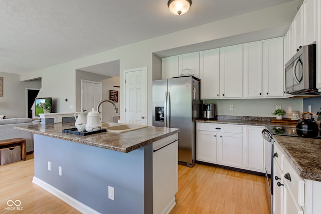 7452 Lace Bark Ct, Avon, IN 46123 - kitchen with stainless steel appliances, dark countertops, light wood finished floors, a center island with sink, and white cabinets