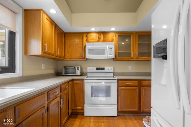 740 Carya Sq, Columbus, IN 47201 - kitchen featuring white appliances, brown cabinetry, light countertops, glass insert cabinets, and light wood-style floors