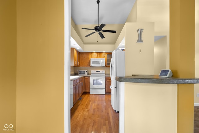 740 Carya Sq, Columbus, IN 47201 - kitchen featuring white appliances, light wood-style floors, brown cabinetry, ceiling fan, and a peninsula