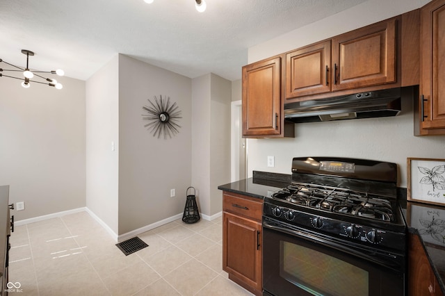 5232 E 10th St, Indianapolis, IN 46219 - kitchen featuring black gas range oven, under cabinet range hood, brown cabinets, a chandelier, and light tile patterned flooring
