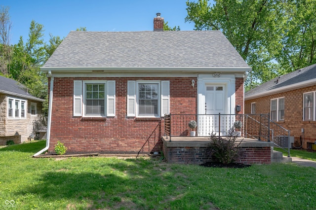 5232 E 10th St, Indianapolis, IN 46219 - view of front facade with brick siding, a chimney, a front lawn, roof with shingles, and central AC