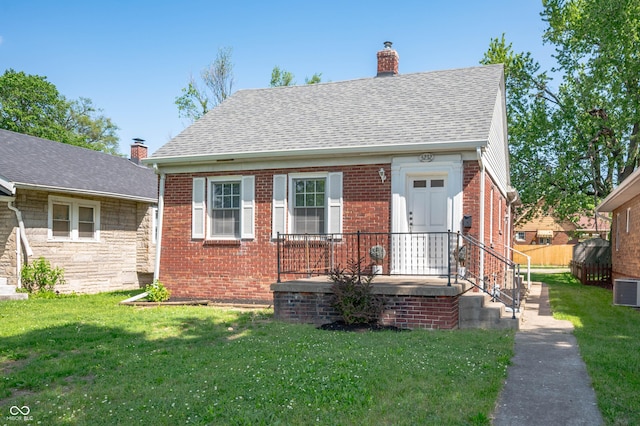 5232 E 10th St, Indianapolis, IN 46219 - view of front facade with a chimney, a front yard, a shingled roof, and brick siding